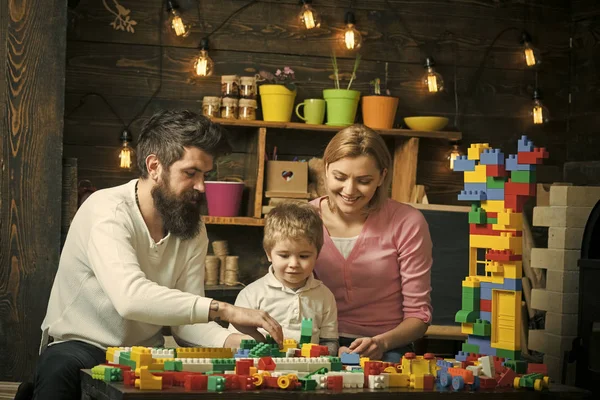 Tiempo libre familiar. Mamá, papá y el niño concentrado ocupados jugando con bloques de plástico. Hijo viendo a sus padres poner ladrillos de construcción juntos — Foto de Stock
