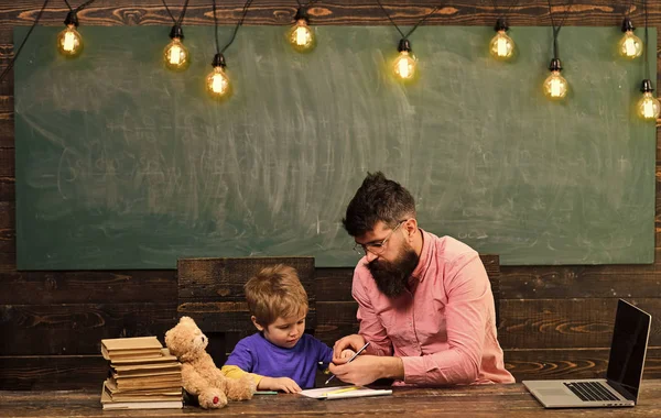 Ucznia z nauczycielem w szkole. Nauczyciel pomaga dziecko do pisania listów w rezerwowym. Mężczyzna i chłopiec siedzą przy biurku z laptopa i stos książek — Zdjęcie stockowe