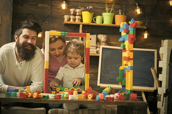 Familia jugando con constructor en casa. Padre, madre e hijo juegan cerca de la construcción de marcos grandes hechos de ladrillos de juguete, bloques de plástico. Madre e hijo lindo juegan con constructor. Concepto de tiempo familiar . — Foto de Stock