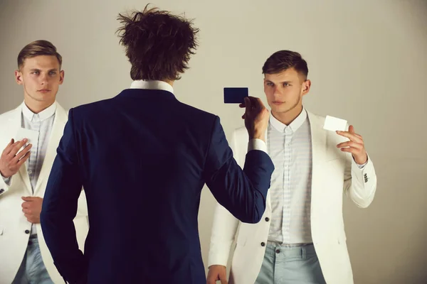 Бізнесмени обмінюються картками на сірому фоні — стокове фото