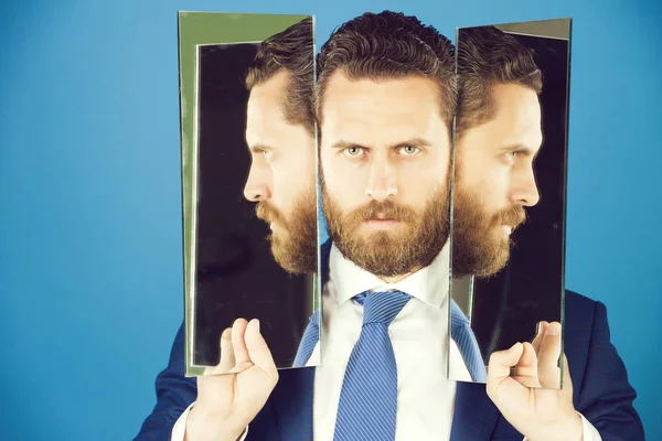 Бізнесмен з бородою, тримає дзеркало з відображенням обличчя — стокове фото