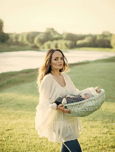 Mother hold baby son in basket on natural landscape