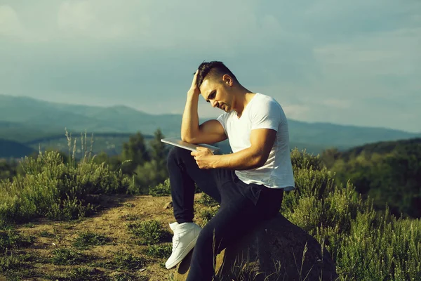Zamyšlený svalnatý muž s notebookem venkovní — Stock fotografie