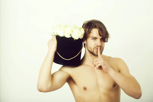 man showing silence finger gesture with roses in box