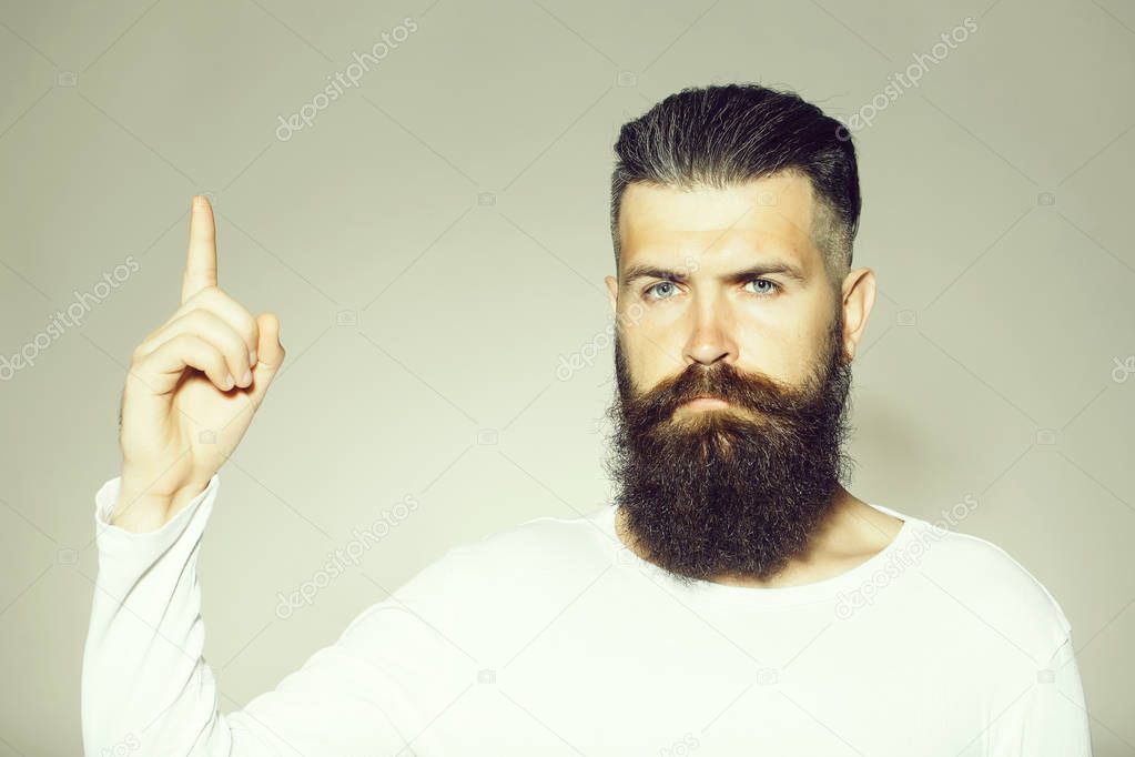 handsome young man with long beard and moustache on face with raised finger on grey background in studio