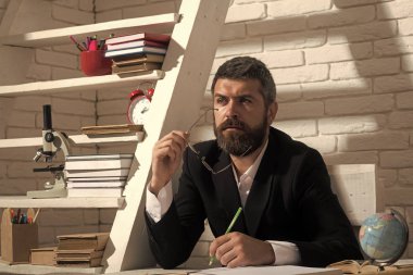 Profesör konsantre yüz ifadesi ile masa başında oturur