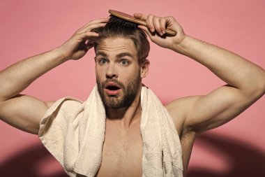 Maço yüz, seksi göğüs banyo havlusu şaşırttı. Adam fırça saç saç fırçası üzerinde pembe bir arka plan ile. Saç bakım, sağlık, sağlık. Güzellik, bakım, hijyen. Sabah rutin kavramı.
