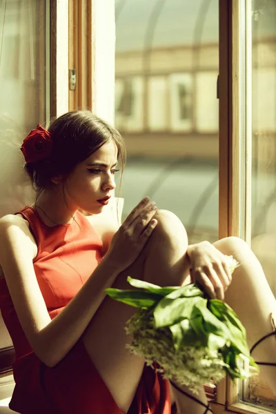 Bela menina espanhola sentada na janela com buquê de flores — Fotografia de Stock