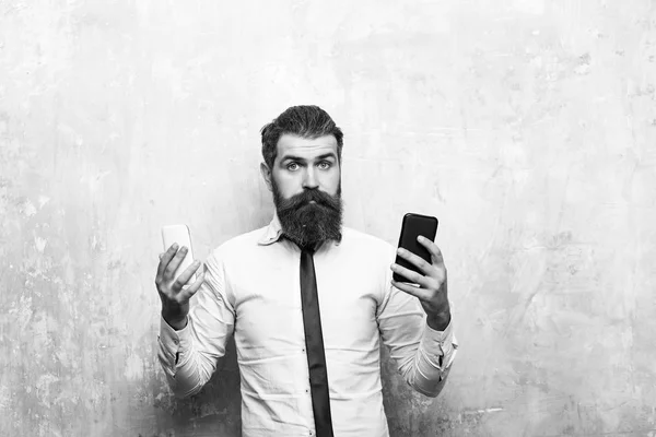 Parrakas mies tai hipster vertailla matkapuhelin ja älypuhelin — kuvapankkivalokuva