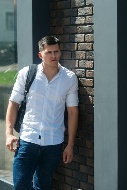 Duvarlar binasının yanında sırt çantası taşıyan yakışıklı genç