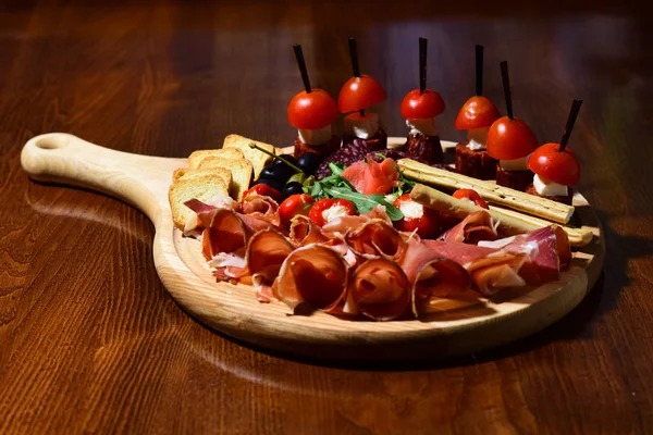 Comida para picar. Carne y canapé en tabla de madera en el mostrador de aperitivos. Perseguir los sabores —  Fotos de Stock