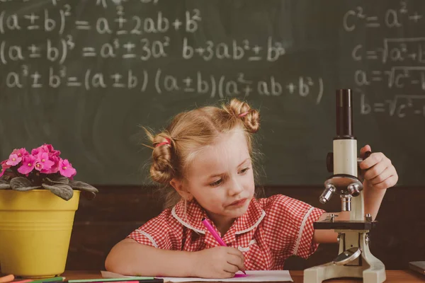 Bambina con microscopio nel laboratorio scolastico. Studentessa lavora con attrezzature di laboratorio in chimica o biologia, filtro vintage — Foto Stock