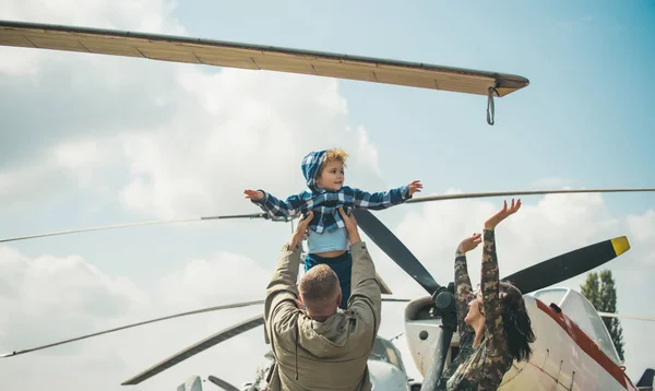 Conceito de sonho. Criança a sonhar voar no céu num avião. Pequeno filho sonhando em ser piloto nas mãos dos pais no show aéreo militar. Sonhando um sonho — Fotografia de Stock