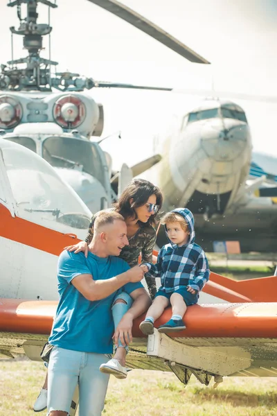 Ferienkonzept. glückliche Familie genießt Sommerurlaub bei Militärflugschau. Kind mit Mutter und Vater sitzen im Urlaub auf Flugzeugflügel. Familienurlaub und Urlaub — Stockfoto