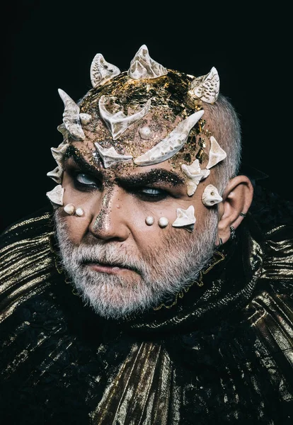 Rey malvado del inframundo con espinas en la cara y barba blanca con traje metálico oscuro aislado sobre fondo negro. Cabeza de demonio con mirada enojada, concepto de fantasía — Foto de Stock