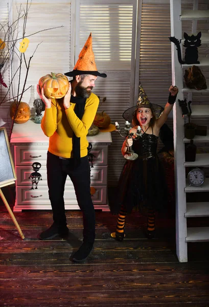 Bambina e padre festeggiano Halloween. Padre e bambina godono di Halloween. Uomo e bambino festeggiano Halloween. L'uomo tiene la zucca intagliata. Avere brividi ed emozioni ad Halloween — Foto Stock