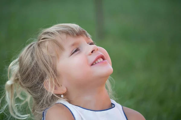 Kid met blond haar glimlach op groen gras — Stockfoto