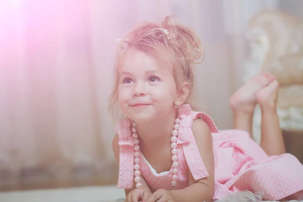 Bambino con sorriso carino in abito rosa si trovano su tappeto — Foto Stock