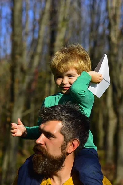 Padre e hijo lanzan avión de papel en el parque. Padre e hijo juegan juntos al aire libre. Agarra diversión con los viajes — Foto de Stock