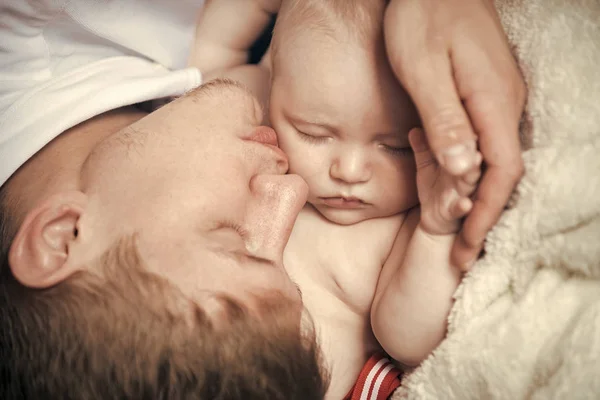 Baby son and father sleep on blanket