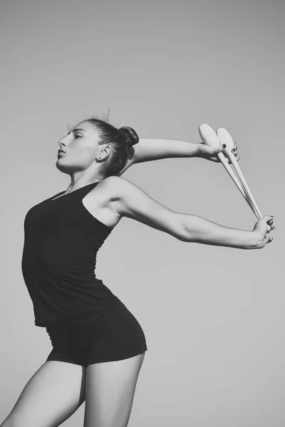 Woman gymnast in black sportswear with green mace.