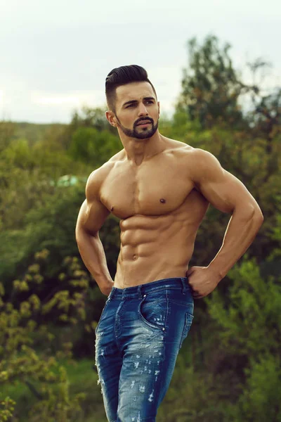 Hombre con cuerpo muscular sobre fondo natural — Foto de Stock