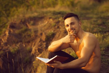 Kitap açık ile gülümseyen kaslı adam