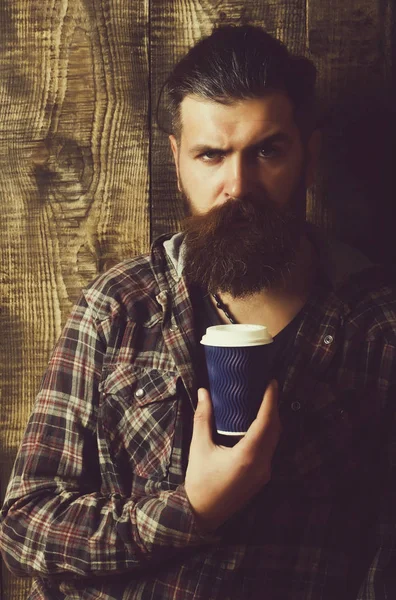 Hipster barbuto accigliato in posa con tazza di plastica blu — Foto Stock