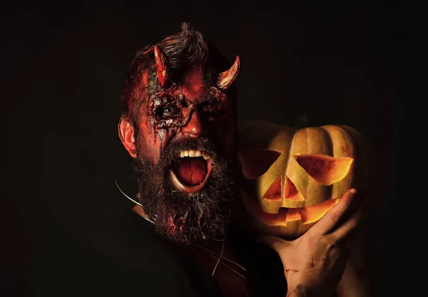 Halloween man devil holding pumpkin on black background