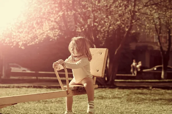Flickan sitter på gungbräda på solig dag — Stockfoto