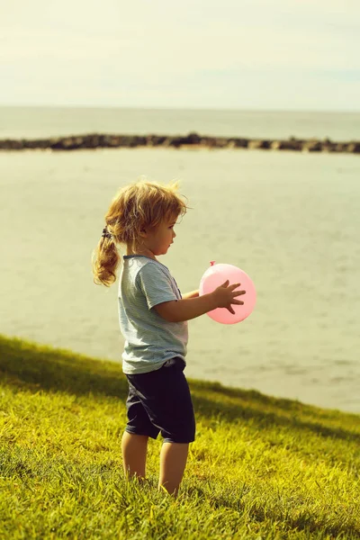 Cute baby boy plays with pink toy balloon — Stock Photo, Image