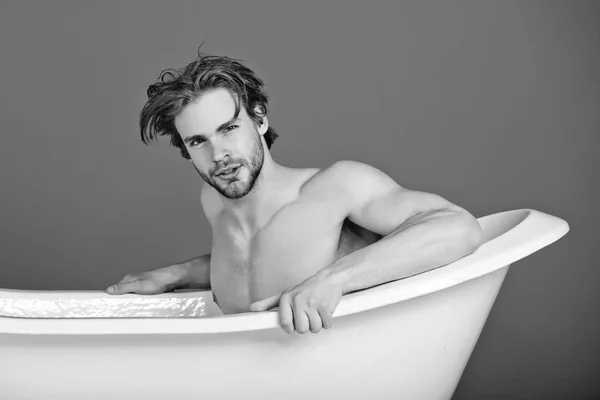 リラックスと衛生、白い浴槽で筋肉ボディを持つ男 — ストック写真