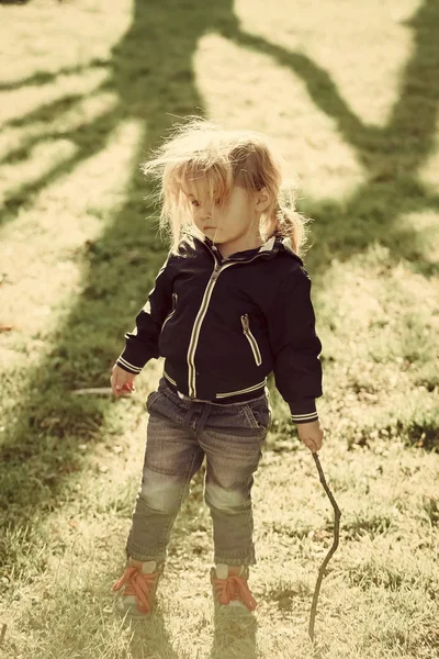 Niño niño en chaqueta azul y jeans jugar con palo —  Fotos de Stock