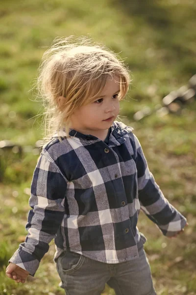 Малыш с светлыми волосами в клетчатой голубой рубашке, джинсах — стоковое фото