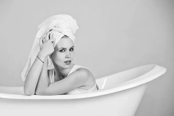 Mulher com turbante de toalha sentado na banheira branca — Fotografia de Stock