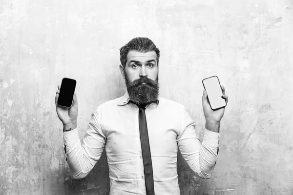 Hipster ou homem barbudo comparar telefone celular e smartphone — Fotografia de Stock