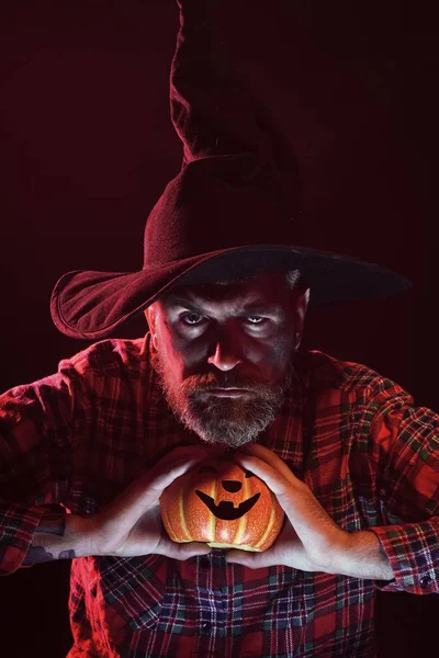 Halloween uomo in cappello strega tenendo zucca al buio — Foto Stock