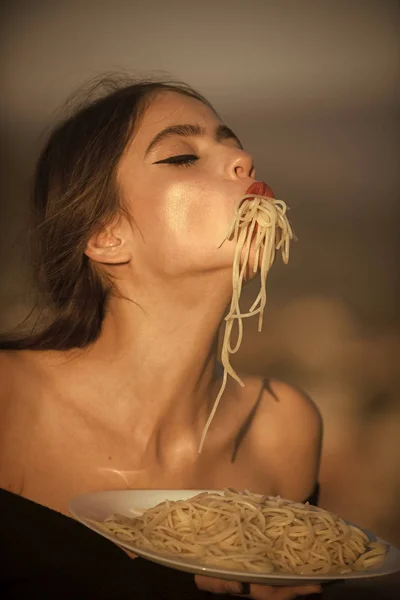 Dieta y alimentos orgánicos saludables, italia. Macarrones italianos o espaguetis para la cena, cocinar. Chef mujer con labios rojos comer pasta. Hambre, apetito, receta. Mujer comiendo pasta como catador o crítico de restaurante — Foto de Stock