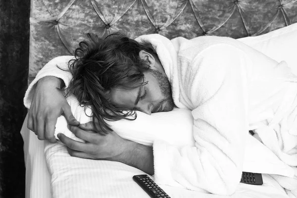 Sakallı adam yatakta uzaktan kumandalı — Stok fotoğraf