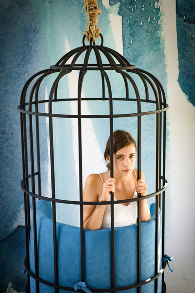 freedom of cute girl in cage. got something on her mind. woman in iron cage. fashion slave in captivity of beauty. prisoner woman in cage - home confinement. modern furniture design and home comfort