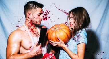 Seksi vampir kan onun ağzına kanlı zemin üzerine damlama ile Coule. Halloween tema. Ürpertici korkunç Cadılar Bayramı vampir kız ve kamera seyir ve kabak tutan büyük kaslı adam.