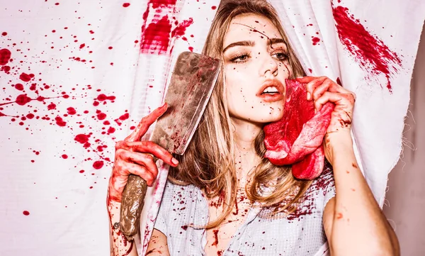 Mujer aterradora con sangre en la cara sosteniendo una cuchilla oxidada y sangrienta y carne delante de su cara. Chica sexy vestido asesino al festival de Halloween. Miedo y horror. Concepto de filete . — Foto de Stock