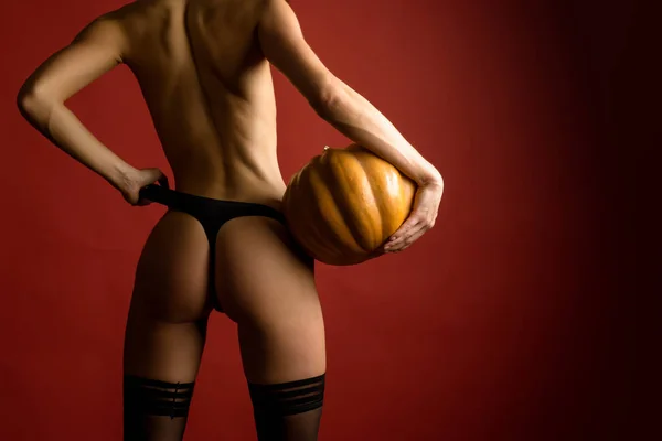 Femme montre un beau cul ou cul. Les bonbons les plus populaires pour Halloween. Concept sexy Halloween. Citrouille avec cul sexy. magasin de vêtements pour femmes célèbre Halloween. Fête de nuit fond . — Photo