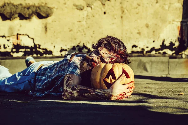 Zombie man lies on pumpkin