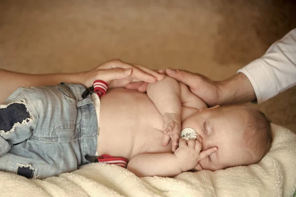 毛布にジーンズで寝るのおしゃぶりを持つ子供 — ストック写真