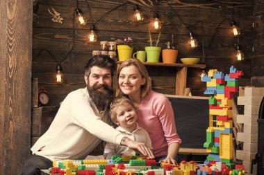 Aile eğlence kavramı. Ebeveynler hugs, oynarken oğlu izlerken, ebeveynlik zevk. Anne ile Çocuk oyun plastik bloklar ile yapı inşaat. Baba, anne ve sevimli oğlu Oluşturucu tuğla ile oynamak