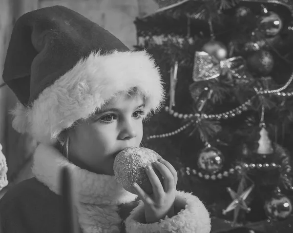 Neujahr kleines Mädchen mit Hut essen Cookie. — Stockfoto