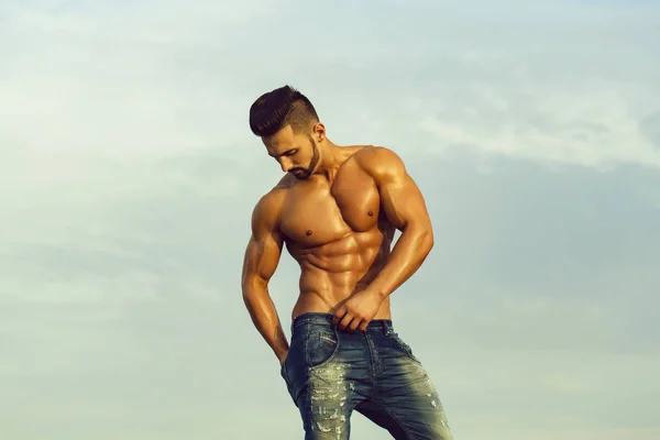 Hombre sexy con el cuerpo muscular en el cielo azul — Foto de Stock