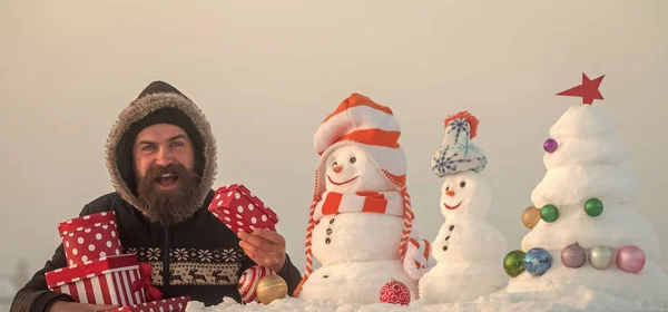Хіпстер посміхається з сніговиками і сніжною ялинкою — стокове фото