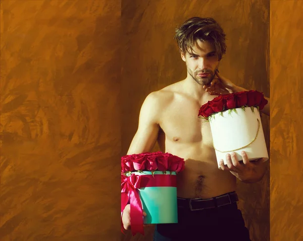 bearded muscular man with sexy body holds red rose box